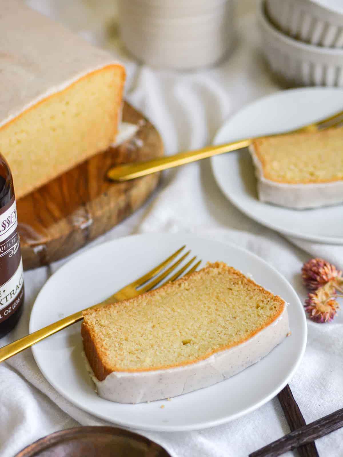 Cake slice on a white plate with a golden fork on side.