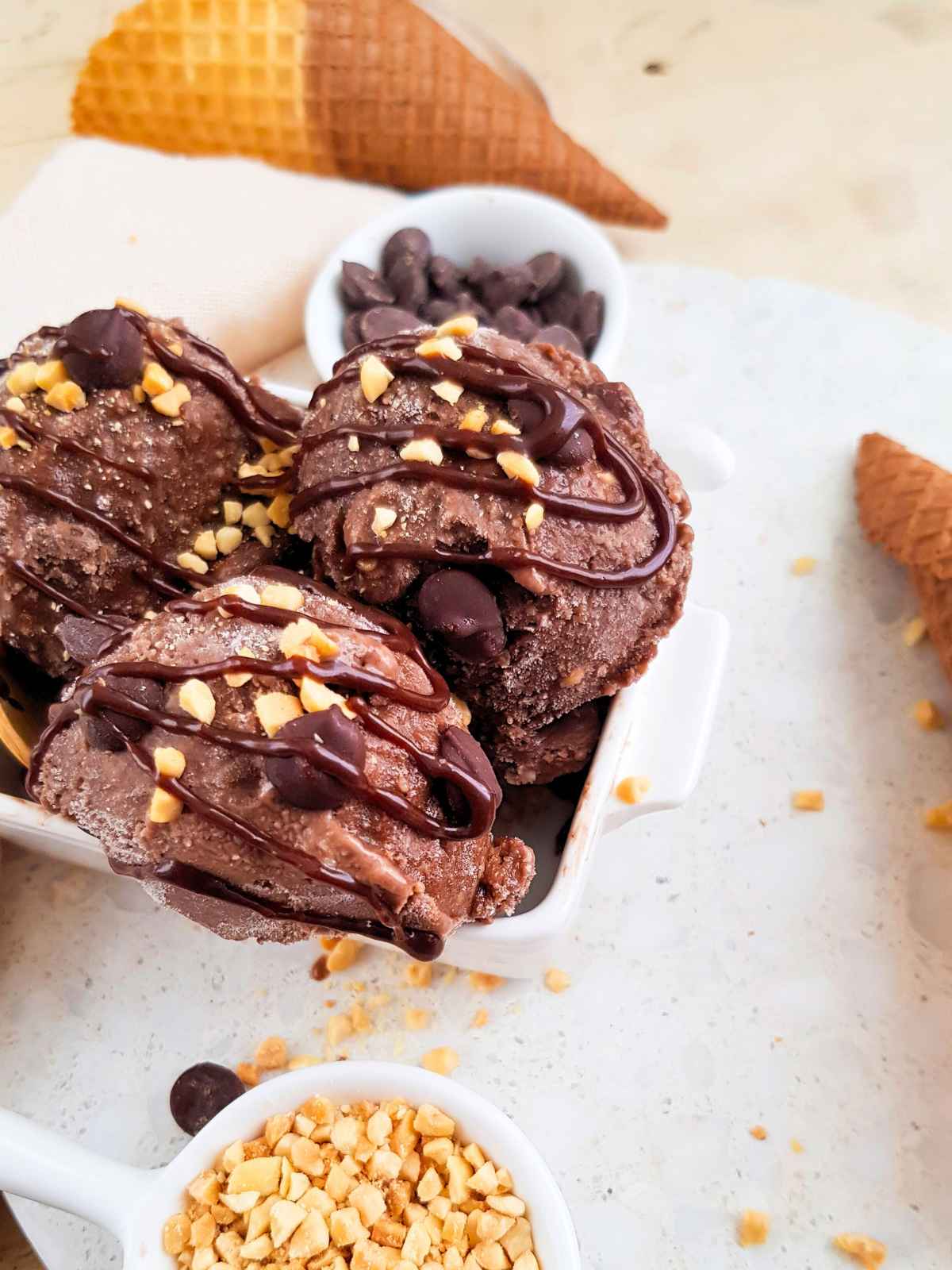 Chocolate Nice Cream scoops in a bowl with chocolate syrup on top.