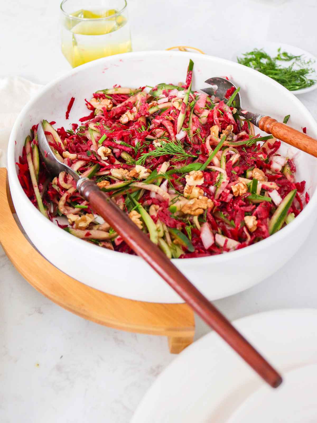 Cucumber Beetroot Salad served in a bowl placed on wooden stand.