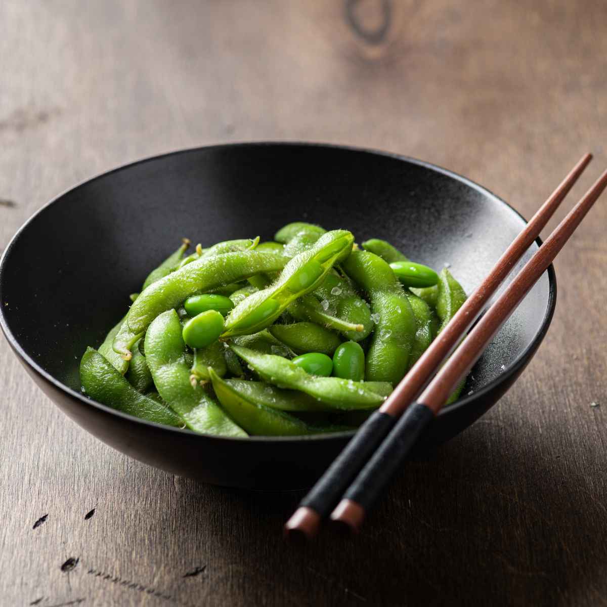 Edamame served in a black bowl.