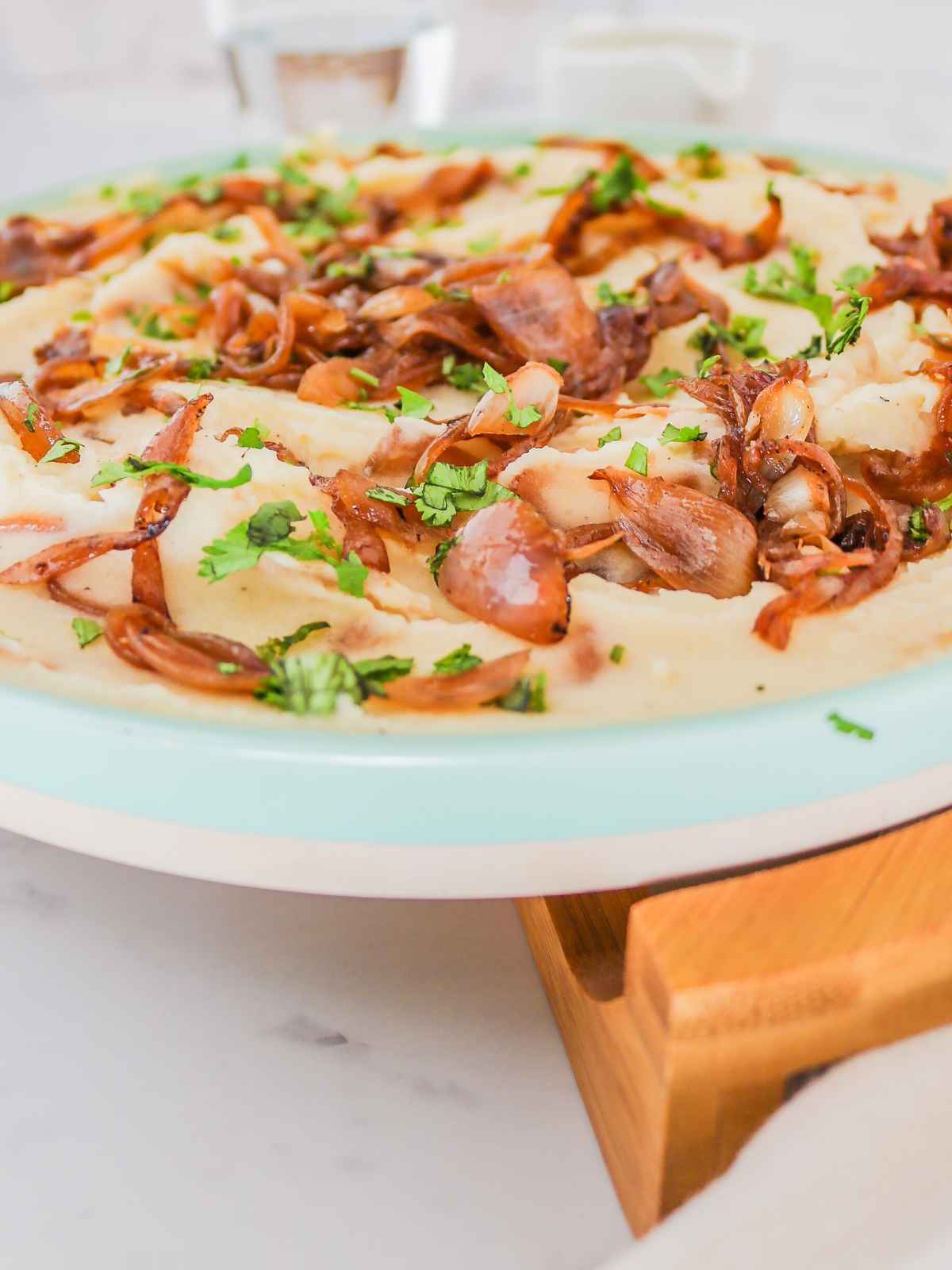 Mashed potatoes topped with caramelized onions and green parsley.
