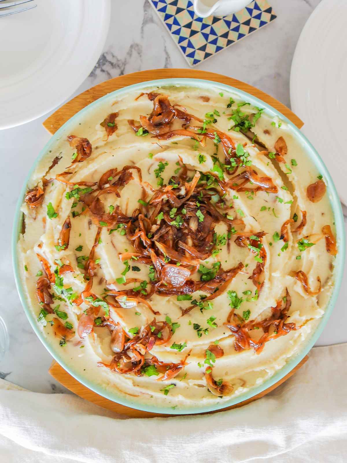 Top view of caramelized onions mashed potatoes served in a plate placed on a wooden frame.