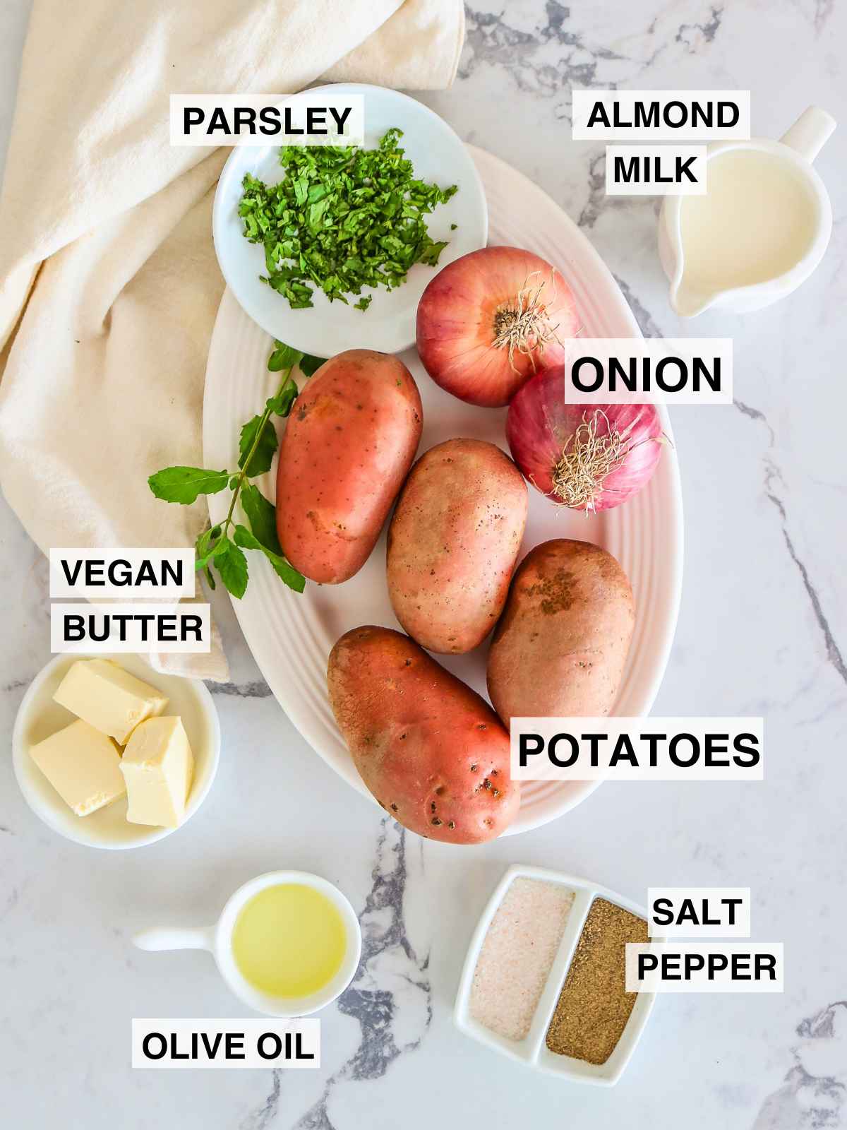 Ingredients placed on a marble top background to make mashed potatoes with caramelized onions.
