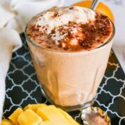 Chocolate mango smoothie in a glass topped with whipped cream