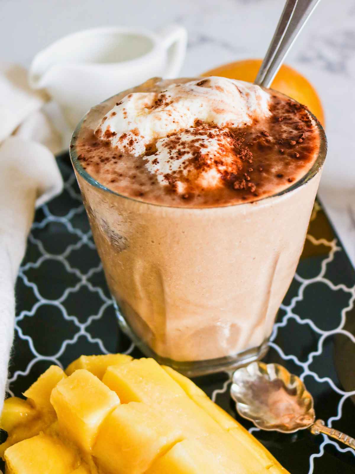 Chocolate mango smoothie severed in a glass topped with cream.