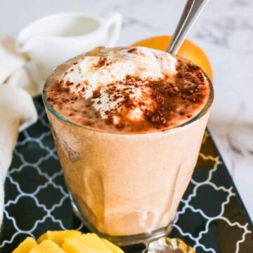 Chocolate mango smoothie in a glass topped with whipped cream