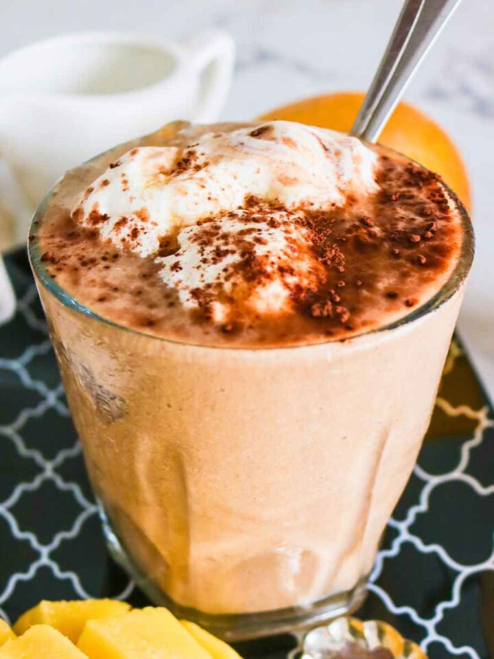 Chocolate mango smoothie in a glass topped with whipped cream