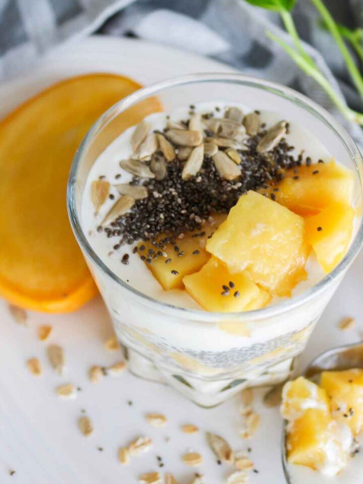 Overnight oats served in a glass jar topped with mango and chia seeds.
