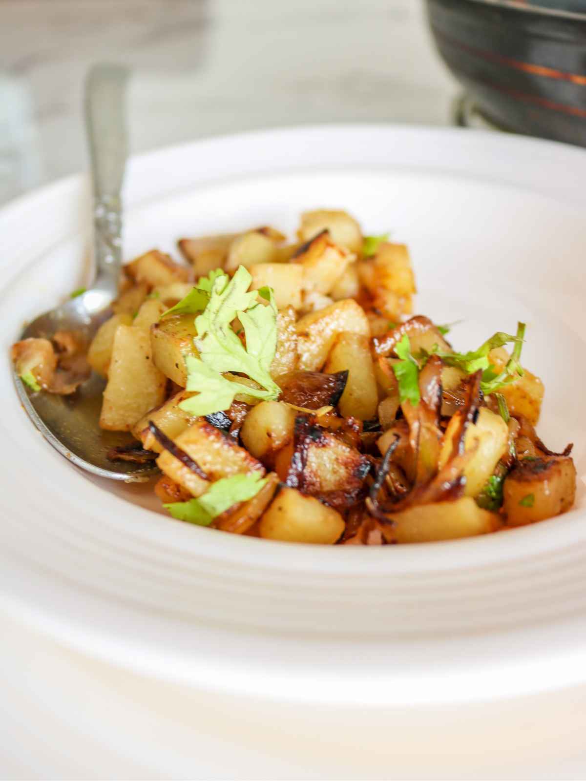 Fried onions and Potatoes served on a white plate.