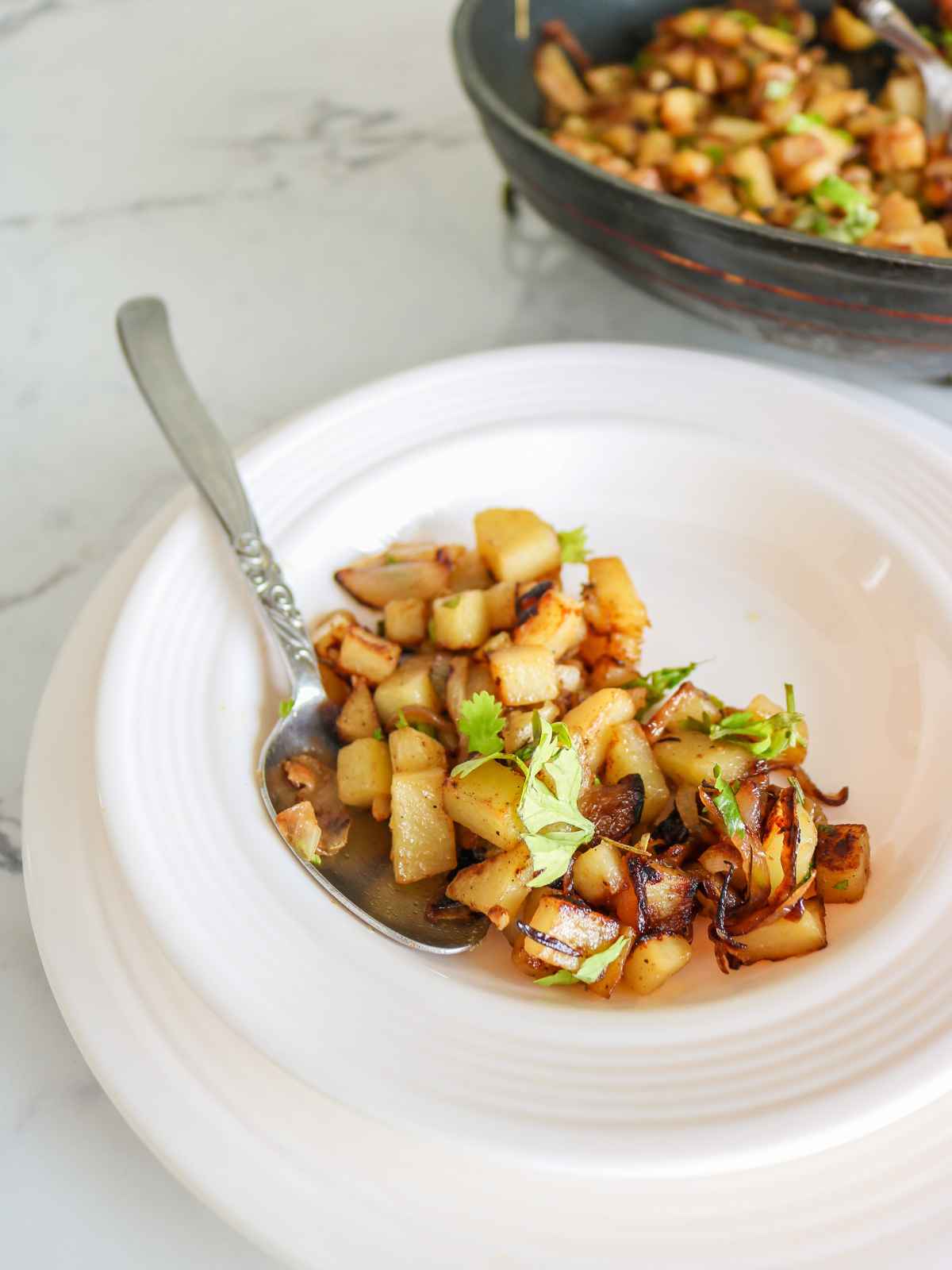 fried Onions and Potatoes served on a white plate.