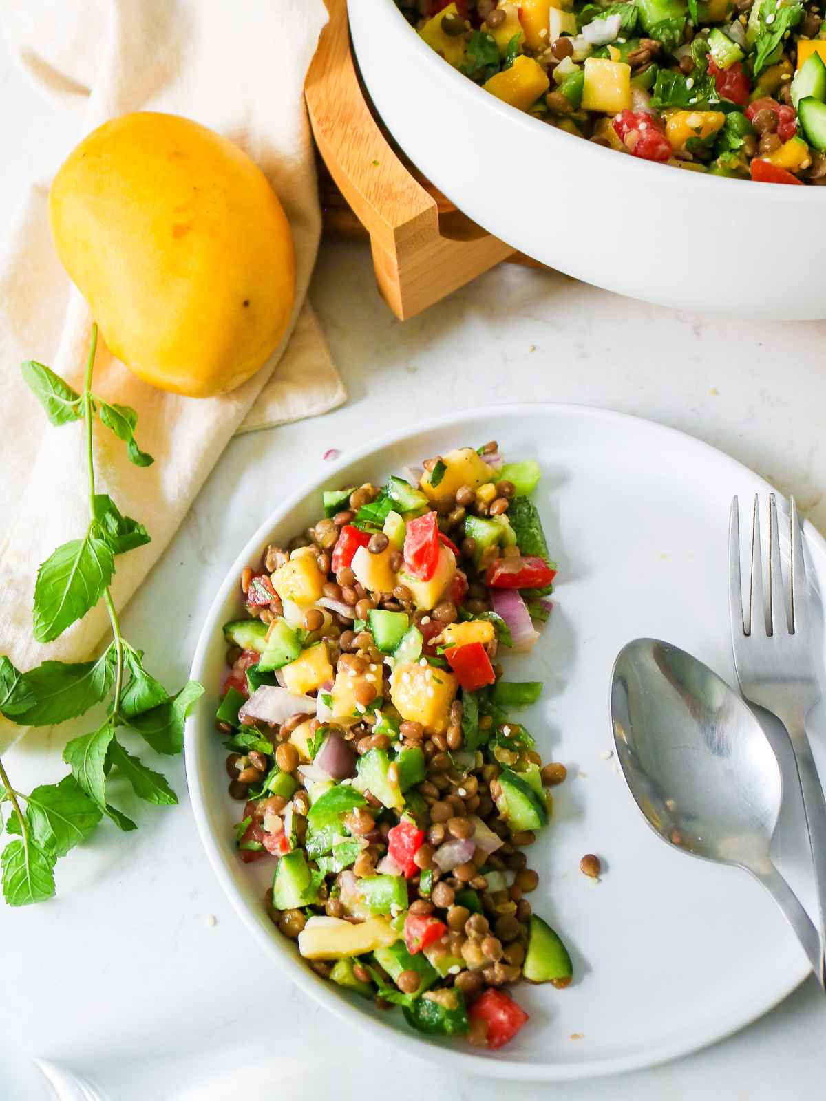 Mango Cucumber Salad in a white plate  with spoon and fork.