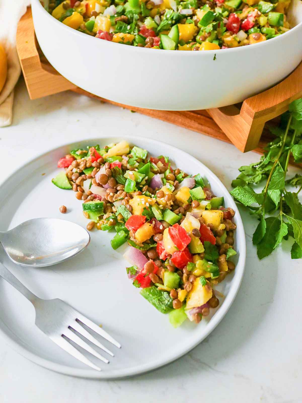 Mango Cucumber Salad in a white plate  with spoon and fork.