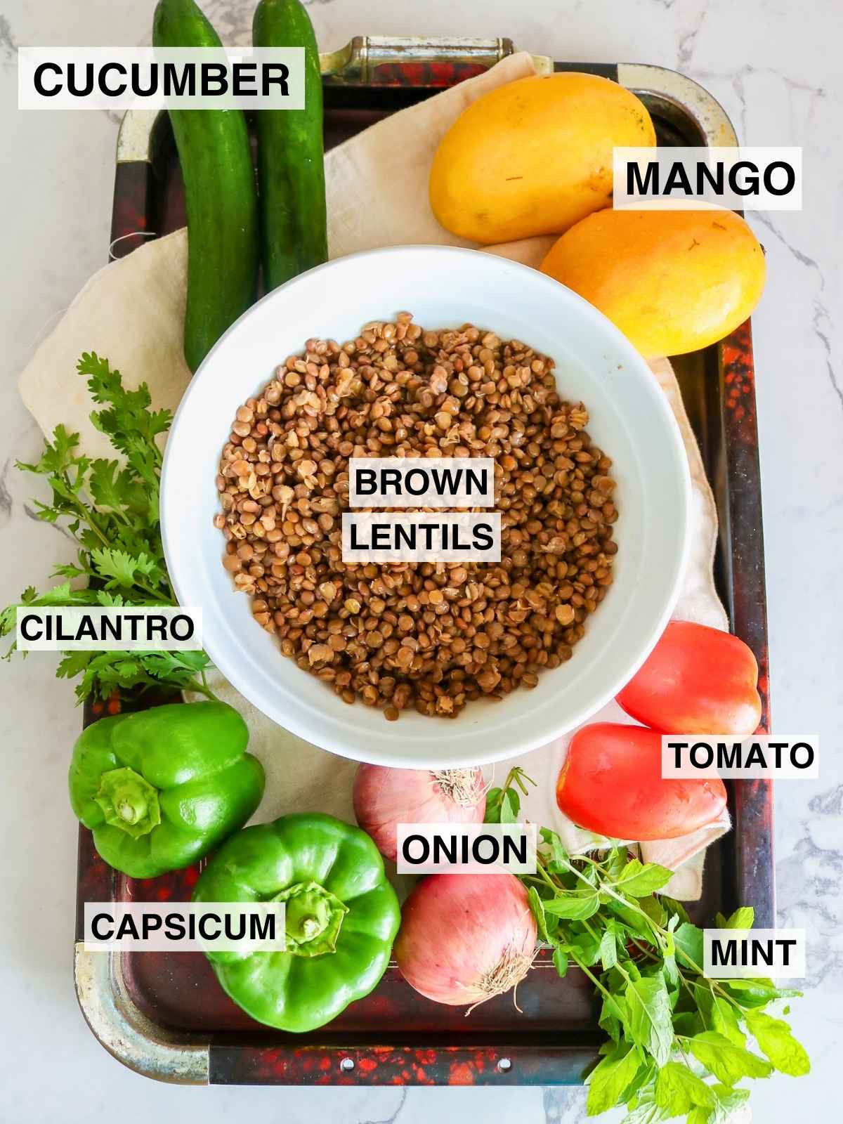 Ingredients to make Mango Cucumber Salad placed in a dark color tray.