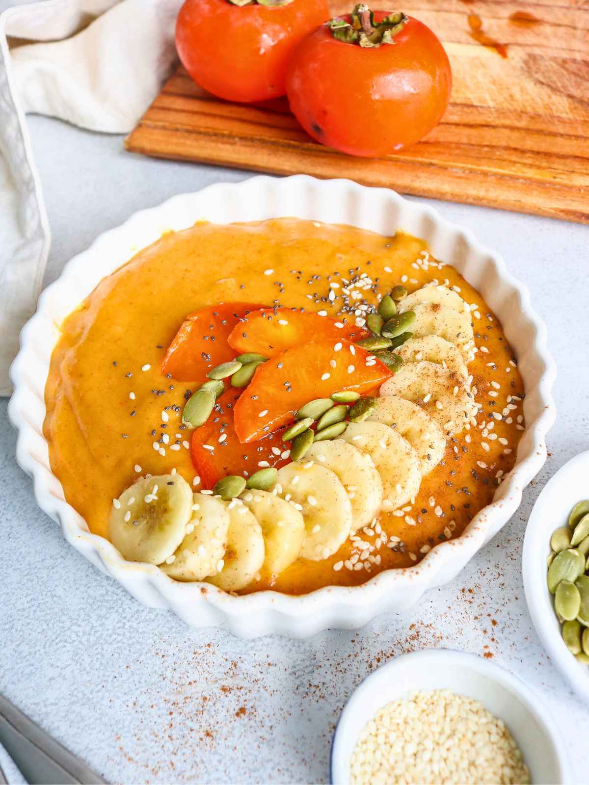 Smoothie bowl in center and wooden board on side. 