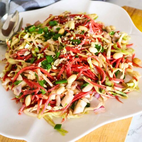 carrot cabbage salad topped with peanuts served on a white plate.