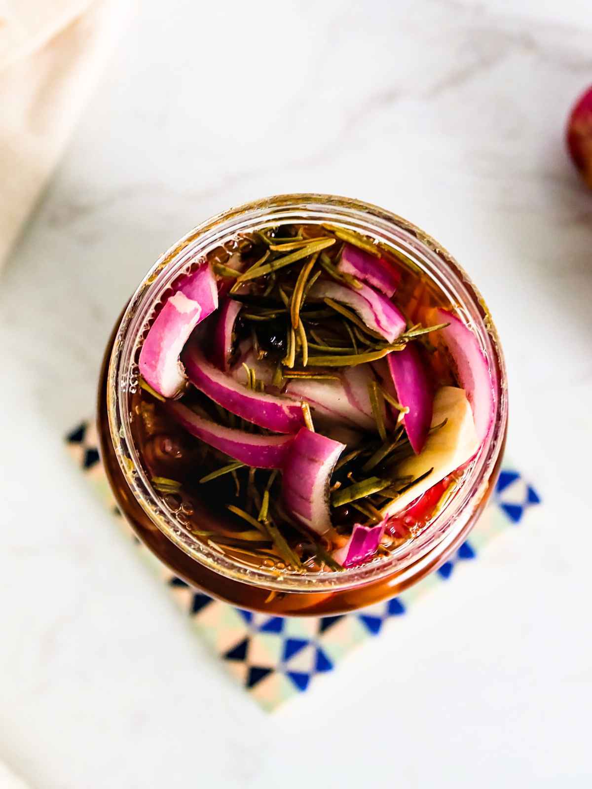 Top view of packed jar with onion and thyme leaves.