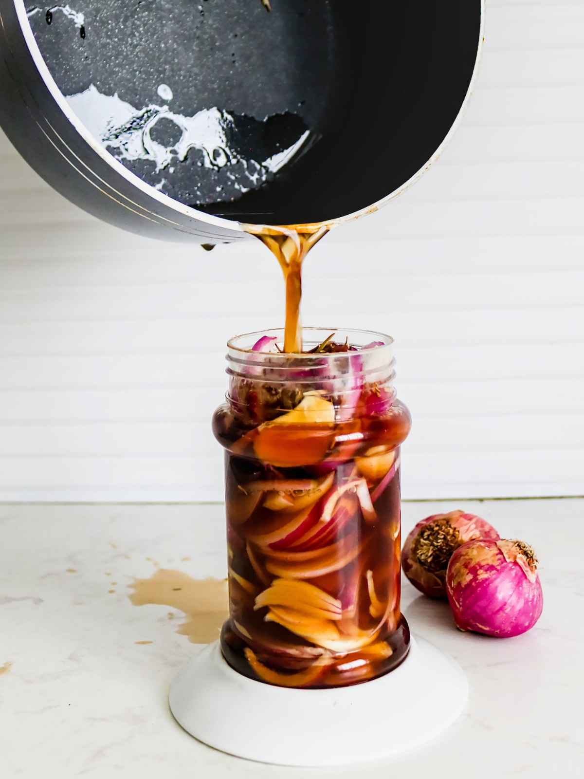 pouring brine over onions in the jar.
