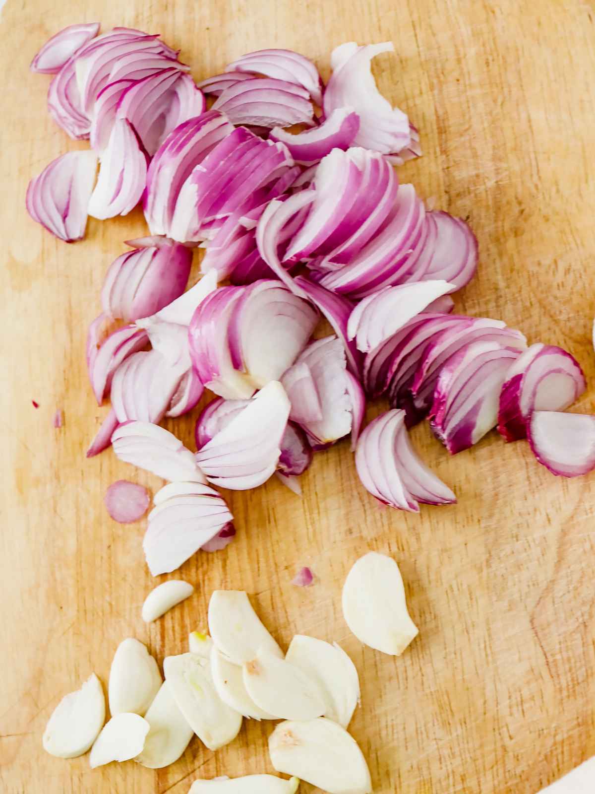 Sliced onions and garlic on a chopping board.